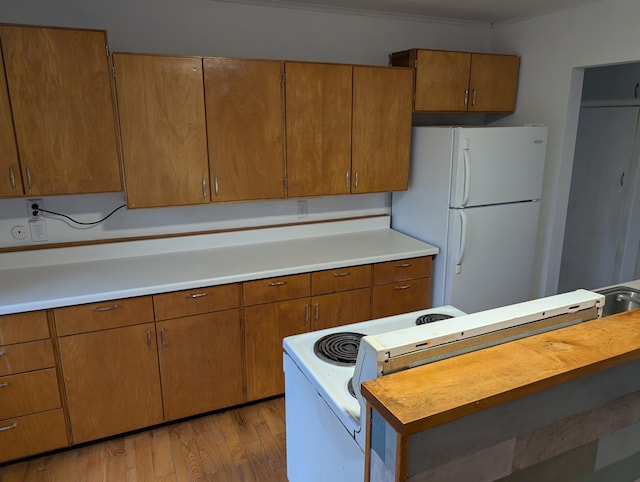 kitchen featuring light wood-style floors, white appliances, light countertops, and brown cabinets