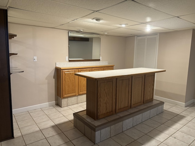 bar featuring light tile patterned flooring, a drop ceiling, and baseboards