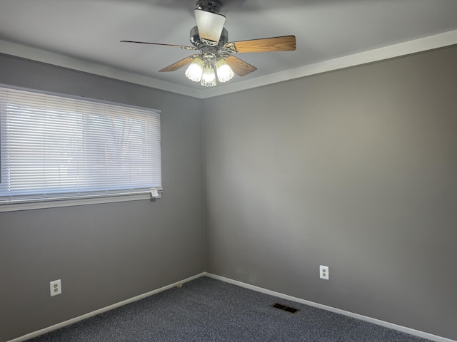 unfurnished room with ceiling fan, dark carpet, visible vents, and baseboards