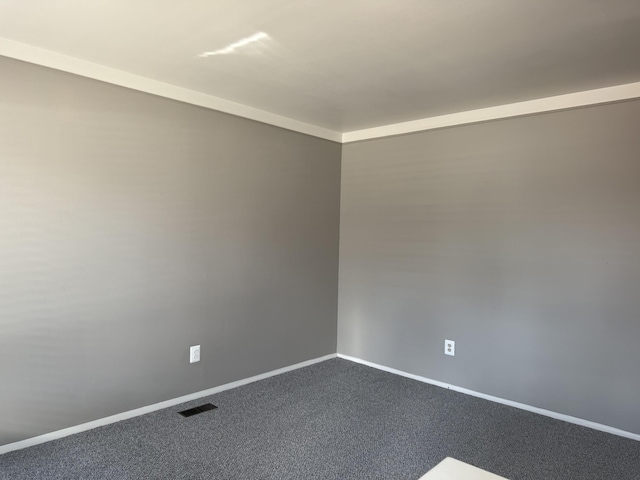 unfurnished room featuring dark carpet, visible vents, and baseboards