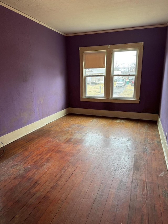 unfurnished room featuring baseboards, wood-type flooring, and crown molding