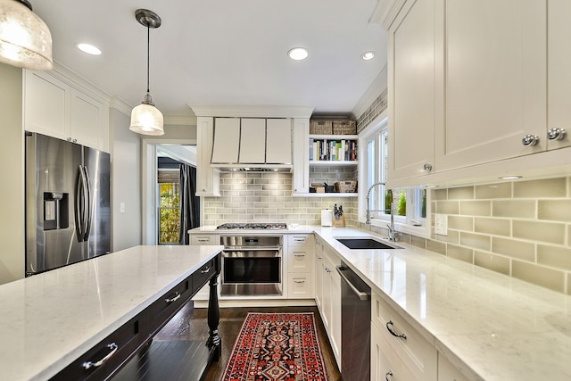 kitchen with a sink, decorative light fixtures, white cabinetry, appliances with stainless steel finishes, and light stone countertops