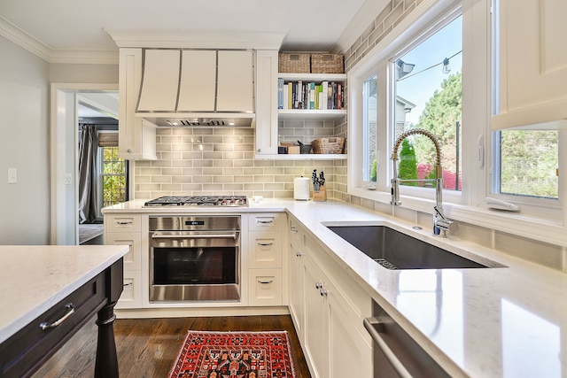 kitchen featuring a sink, stainless steel appliances, light stone counters, and crown molding