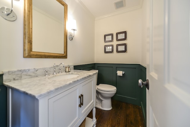 half bath featuring visible vents, toilet, wood finished floors, wainscoting, and crown molding