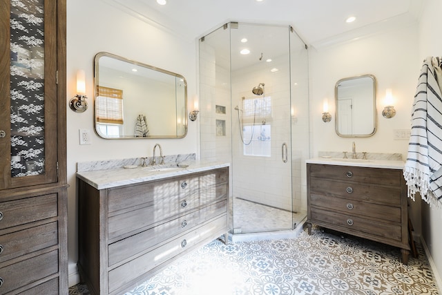 bathroom featuring two vanities, ornamental molding, a shower stall, and a sink