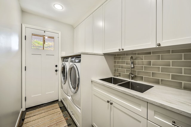 laundry room featuring washing machine and clothes dryer, cabinet space, and a sink