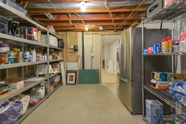 unfinished basement featuring stainless steel fridge with ice dispenser