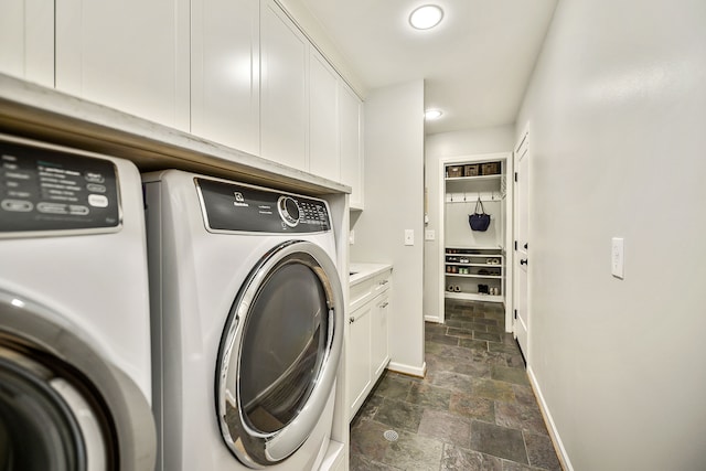 laundry area featuring stone tile flooring, independent washer and dryer, cabinet space, and baseboards