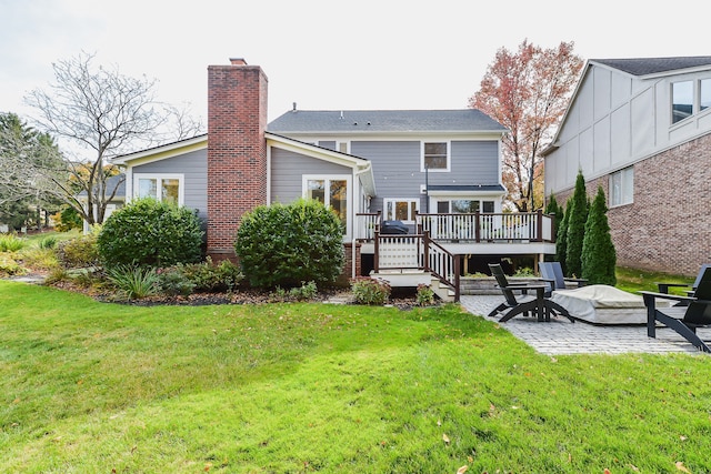 rear view of property with a wooden deck, a patio area, a lawn, and a chimney