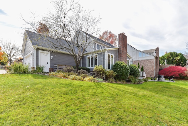 back of property with an attached garage, a yard, and a chimney