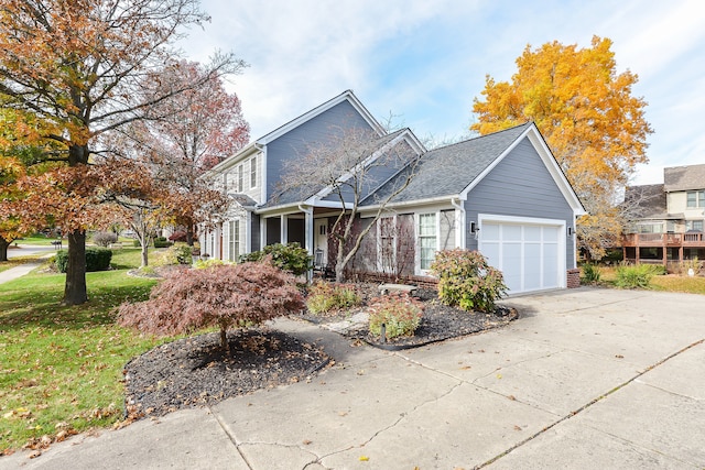 traditional-style home with a garage, roof with shingles, concrete driveway, and a front lawn