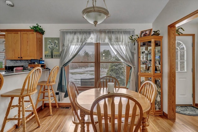 dining space featuring light wood finished floors, visible vents, and baseboards