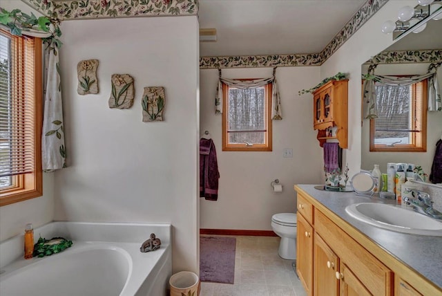 bathroom featuring vanity, toilet, a bath, and baseboards