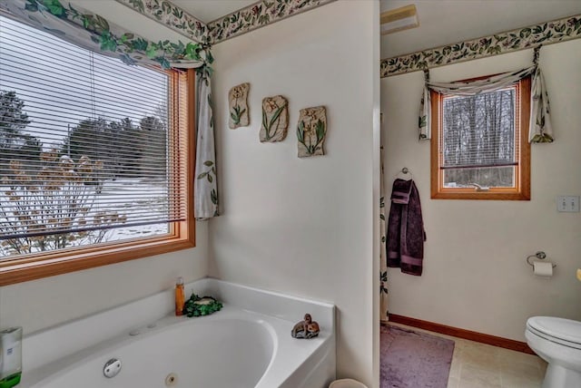 full bathroom with tile patterned floors, toilet, a tub with jets, and baseboards