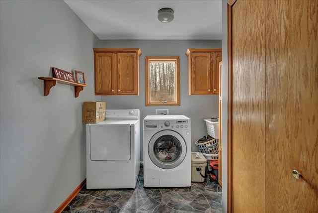 clothes washing area featuring baseboards, cabinet space, and separate washer and dryer