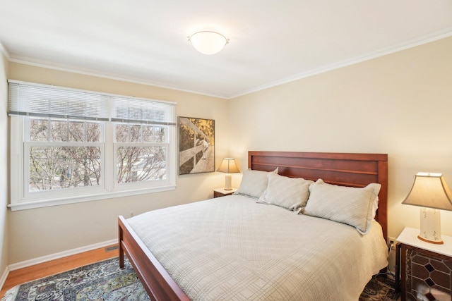 bedroom with multiple windows, crown molding, baseboards, and wood finished floors