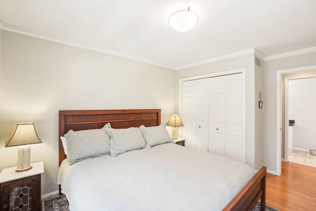 bedroom with a closet, visible vents, ornamental molding, wood finished floors, and baseboards