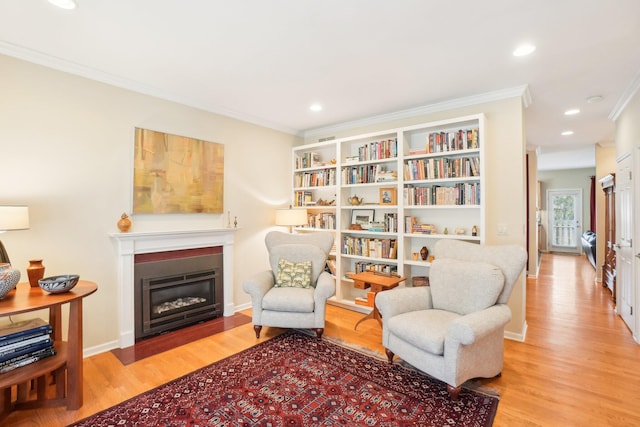 living area with recessed lighting, crown molding, wood finished floors, and a glass covered fireplace