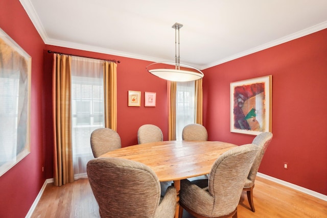 dining room with crown molding, light wood-style flooring, and baseboards