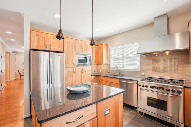 kitchen featuring a sink, wall chimney range hood, appliances with stainless steel finishes, decorative backsplash, and light brown cabinetry