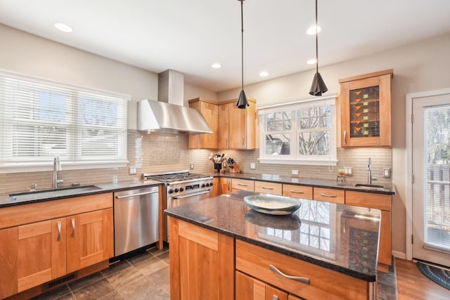 kitchen featuring a sink, appliances with stainless steel finishes, decorative backsplash, dark stone counters, and wall chimney exhaust hood