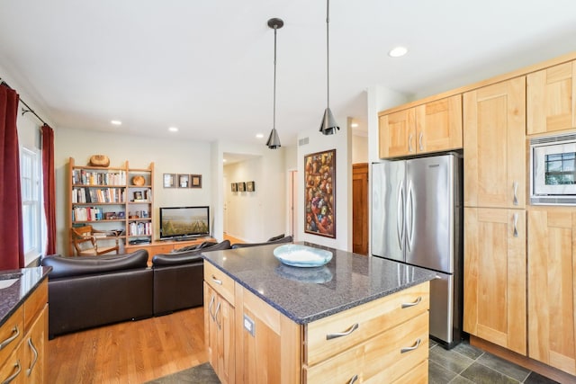 kitchen featuring light brown cabinets, recessed lighting, appliances with stainless steel finishes, a center island, and dark stone countertops