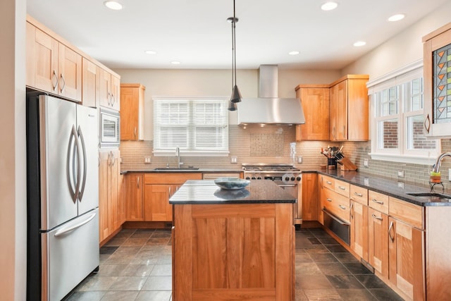 kitchen featuring wall chimney range hood, appliances with stainless steel finishes, a sink, and a center island