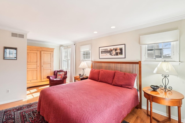 bedroom with visible vents, crown molding, baseboards, and wood finished floors