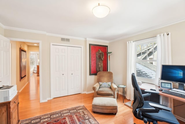 office featuring light wood-type flooring, baseboards, visible vents, and ornamental molding