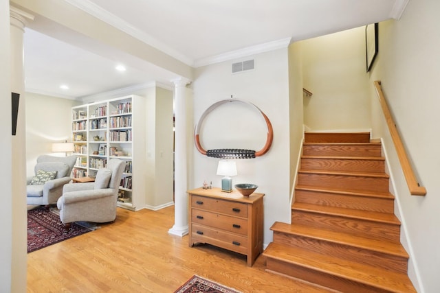 interior space featuring decorative columns, visible vents, wood finished floors, stairs, and crown molding