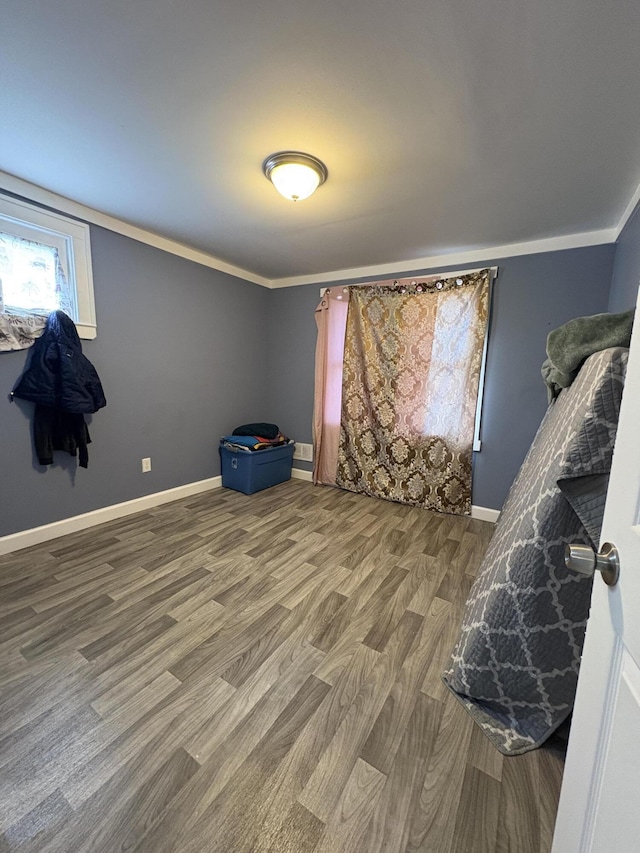 bedroom featuring ornamental molding, wood finished floors, and baseboards