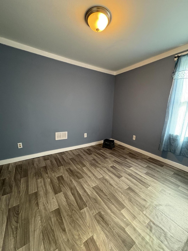 unfurnished room with wood finished floors, visible vents, and baseboards