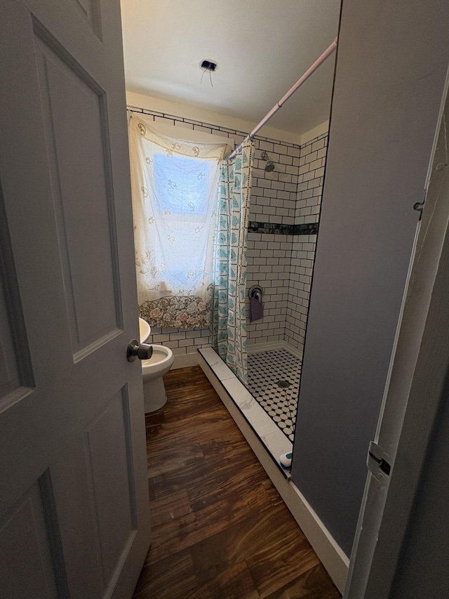 full bathroom with a stall shower, toilet, and wood finished floors