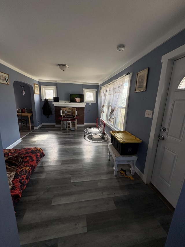 entrance foyer with baseboards, arched walkways, and wood finished floors