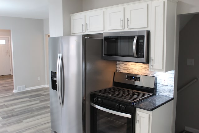 kitchen featuring visible vents, white cabinets, appliances with stainless steel finishes, light wood-type flooring, and backsplash