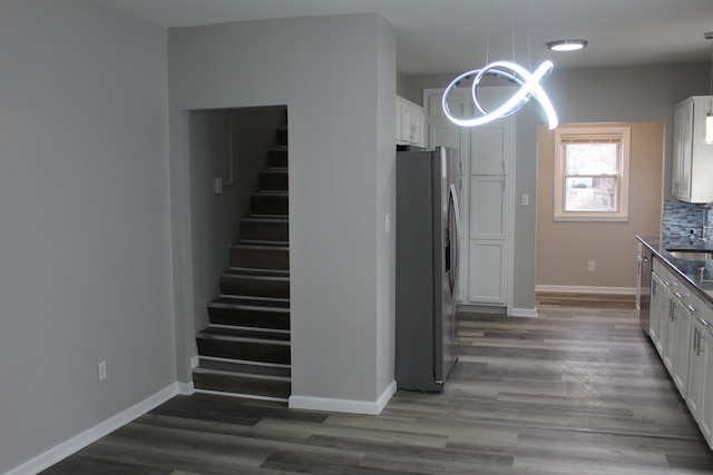 kitchen featuring appliances with stainless steel finishes, dark wood-style flooring, a sink, and baseboards