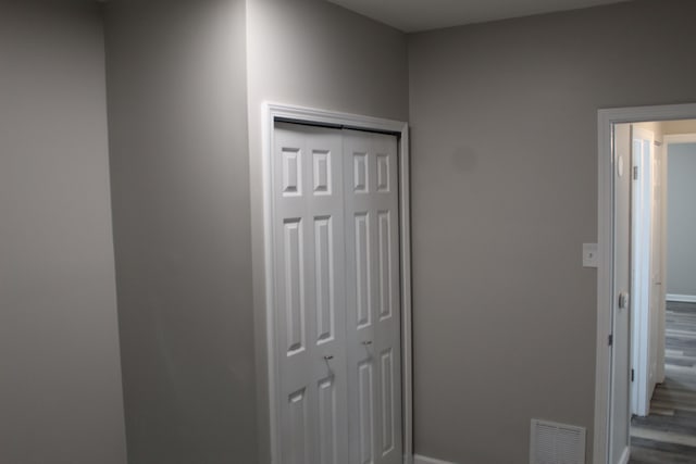 hallway with baseboards, visible vents, and dark wood-type flooring