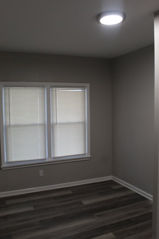 spare room featuring dark wood finished floors and baseboards