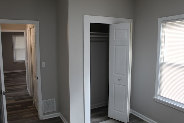 unfurnished bedroom featuring baseboards, a closet, visible vents, and wood finished floors