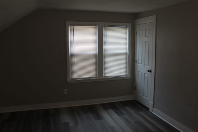 bonus room with dark wood-type flooring, vaulted ceiling, and baseboards