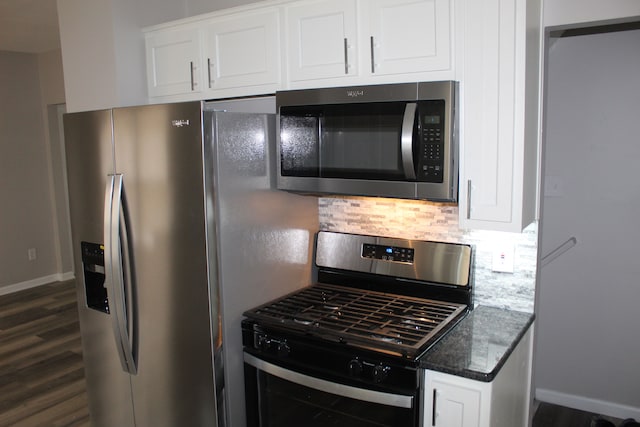 kitchen with dark wood-style floors, tasteful backsplash, appliances with stainless steel finishes, white cabinets, and dark stone countertops