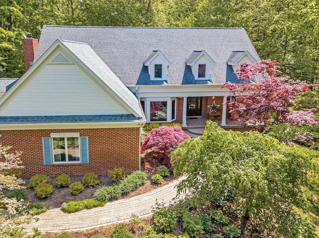 cape cod home with brick siding and roof with shingles