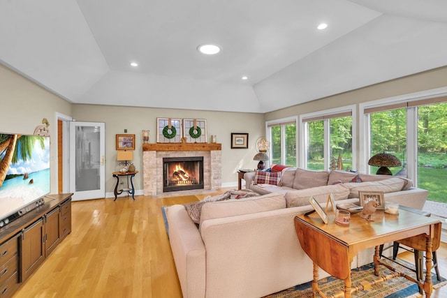 living room with recessed lighting, a fireplace with flush hearth, baseboards, vaulted ceiling, and light wood-type flooring