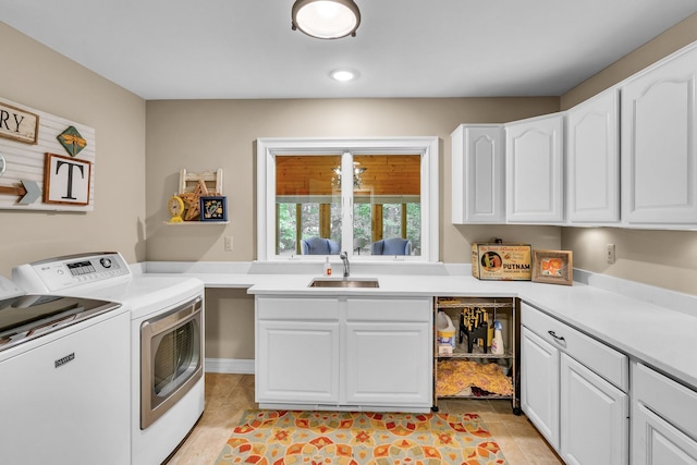 clothes washing area with cabinet space, washing machine and dryer, and a sink