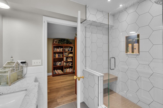 full bath with a stall shower, a sink, and wood finished floors