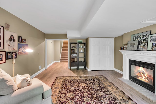 living room with wood finished floors, stairway, a fireplace with flush hearth, and baseboards