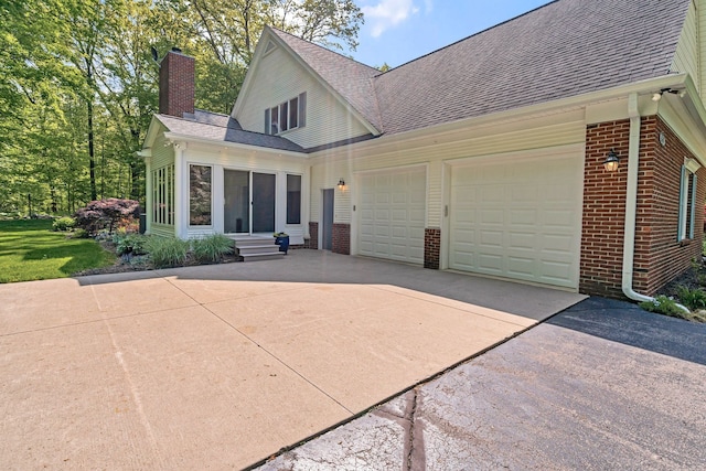 view of front of home featuring concrete driveway, brick siding, and roof with shingles