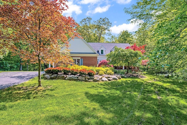 view of front of property with brick siding, driveway, and a front lawn