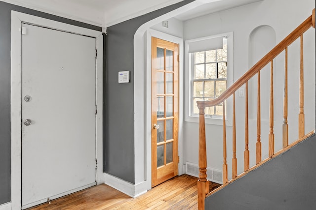 entrance foyer featuring arched walkways, visible vents, stairway, and wood finished floors