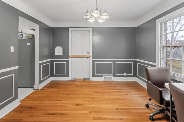 office with a healthy amount of sunlight, visible vents, a decorative wall, and a notable chandelier